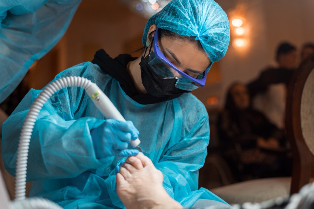 Voluntar realizând o procedură de podologie cu instrument profesional